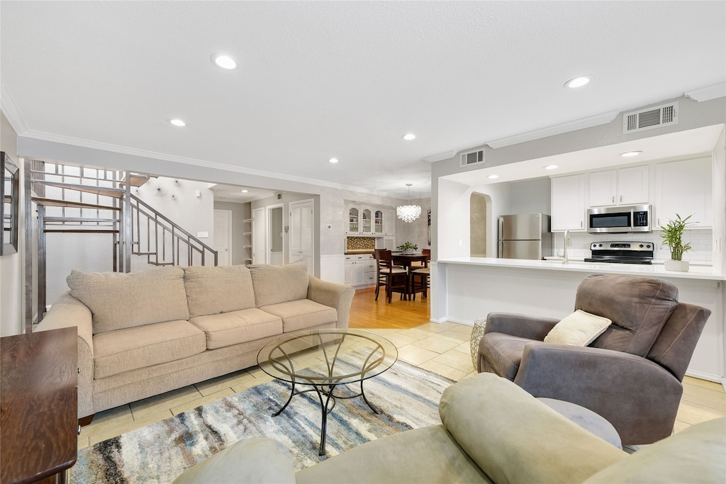 living room featuring light tile patterned floors, an inviting chandelier, ornamental molding, and sink