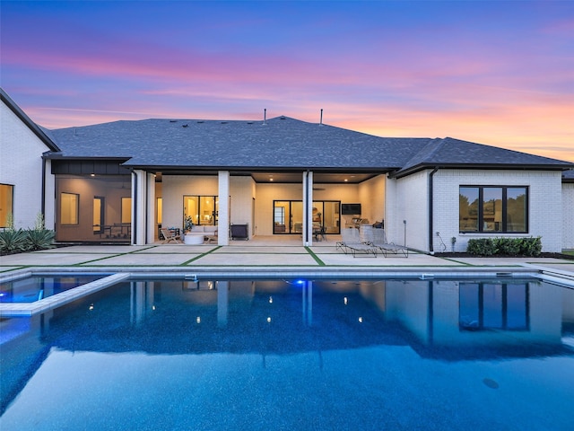 pool at dusk featuring a patio