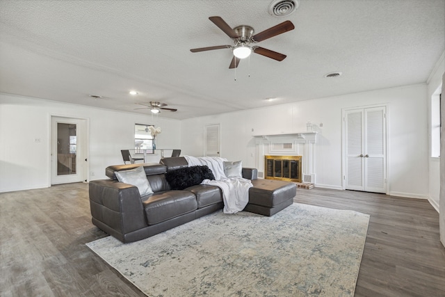 living room with ceiling fan, a textured ceiling, and dark wood-type flooring