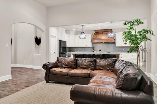 living room featuring arched walkways, recessed lighting, wood finished floors, and baseboards