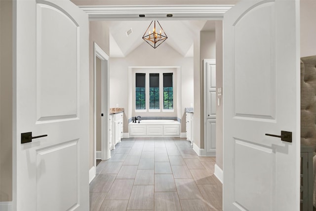 full bath with lofted ceiling, a notable chandelier, visible vents, baseboards, and a bath