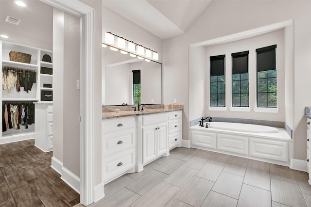 full bath featuring a healthy amount of sunlight, visible vents, vaulted ceiling, and vanity