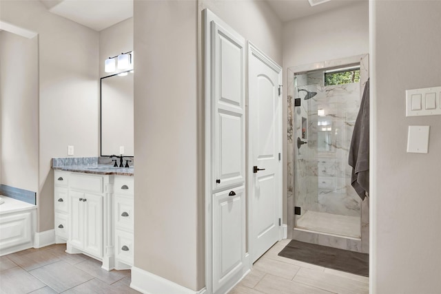 bathroom featuring a marble finish shower, baseboards, and vanity