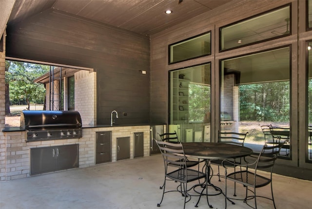 view of patio with outdoor dining space, a sink, a grill, and an outdoor kitchen