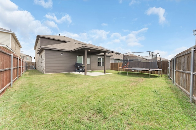 back of property featuring a patio, a lawn, and a trampoline