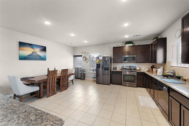 kitchen featuring light tile patterned floors, decorative backsplash, light stone counters, and stainless steel appliances