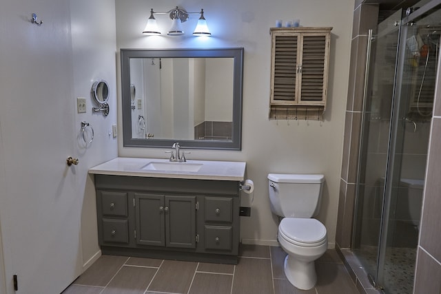 bathroom with tile patterned floors, a shower with shower door, toilet, and vanity