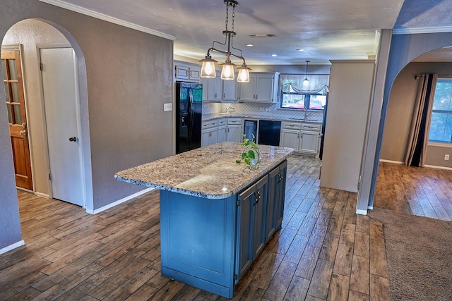 kitchen with black appliances, decorative light fixtures, a center island, backsplash, and ornamental molding