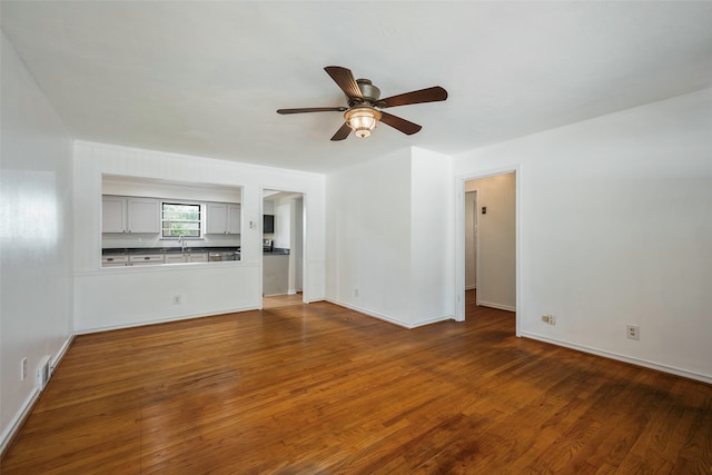 unfurnished living room featuring hardwood / wood-style floors, sink, and ceiling fan