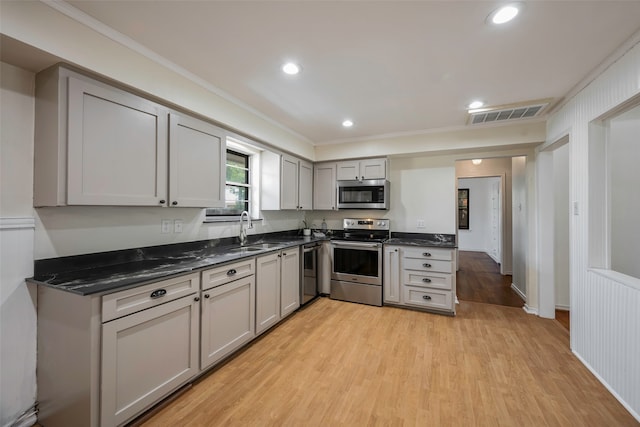 kitchen with gray cabinetry, light wood-type flooring, stainless steel appliances, sink, and ornamental molding