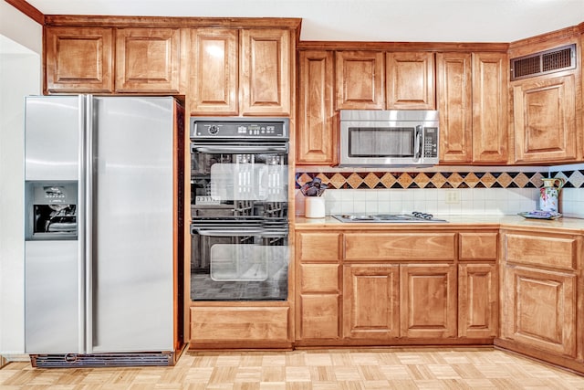 kitchen featuring light parquet floors, appliances with stainless steel finishes, and decorative backsplash