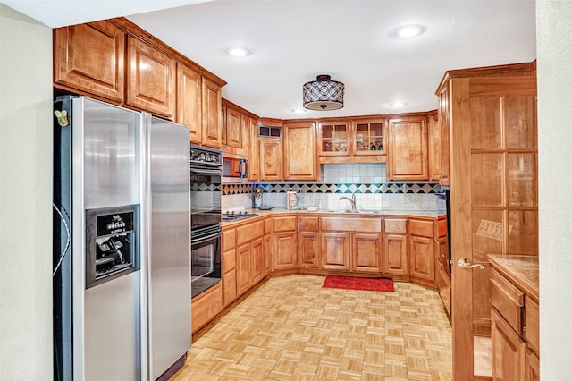 kitchen featuring light parquet floors, backsplash, appliances with stainless steel finishes, tile countertops, and sink