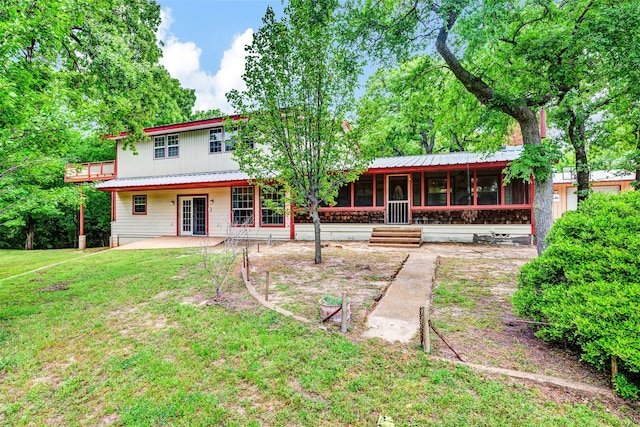 back of house with a sunroom and a lawn