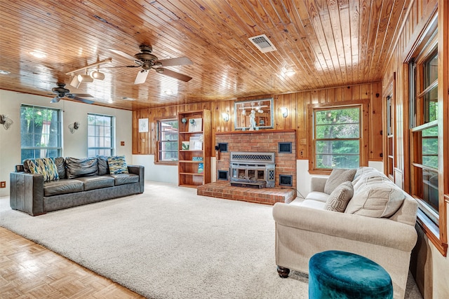 living room with parquet floors, ceiling fan, wooden walls, a brick fireplace, and wood ceiling