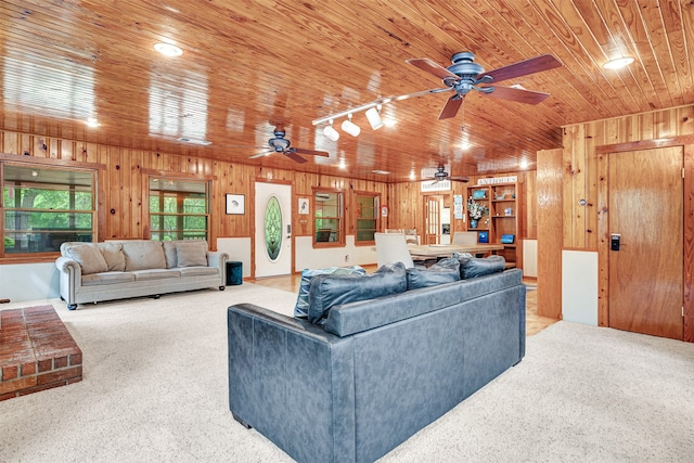 living room featuring track lighting, wooden walls, and ceiling fan