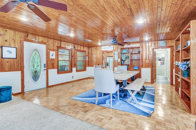 dining room featuring wood walls, light parquet flooring, ceiling fan, and wood ceiling