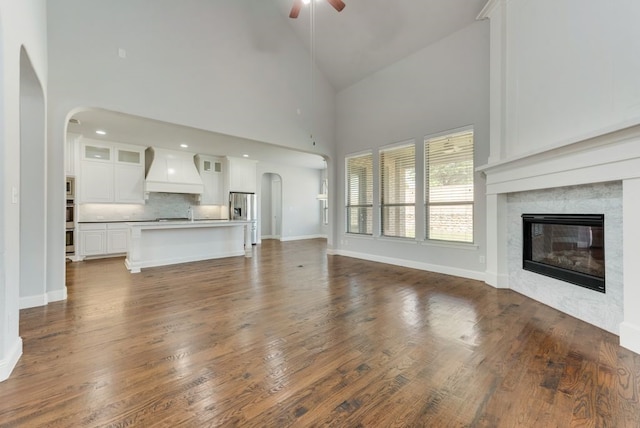 unfurnished living room with hardwood / wood-style flooring, high vaulted ceiling, and ceiling fan