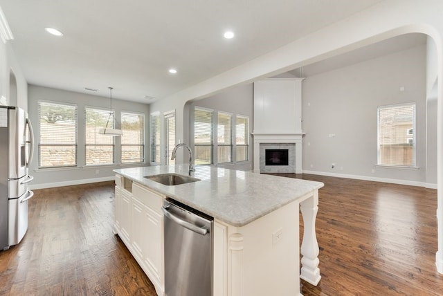 kitchen with appliances with stainless steel finishes, decorative light fixtures, an island with sink, sink, and white cabinets