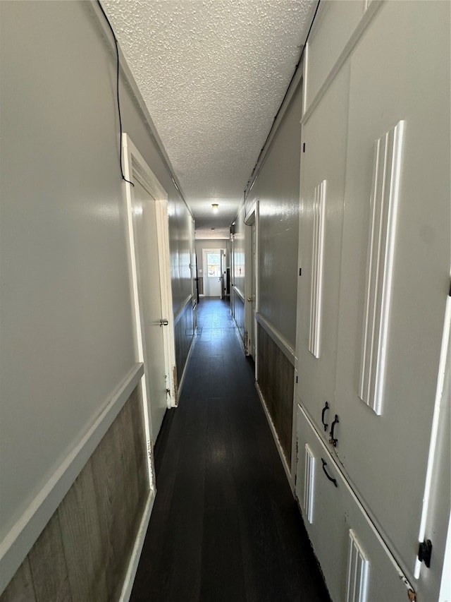 hall with dark wood-type flooring and a textured ceiling