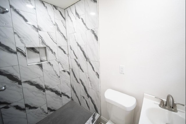 bathroom with sink, toilet, and tiled shower