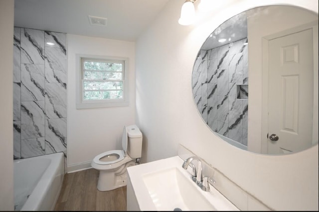 full bathroom featuring hardwood / wood-style flooring, vanity, toilet, and tiled shower / bath combo