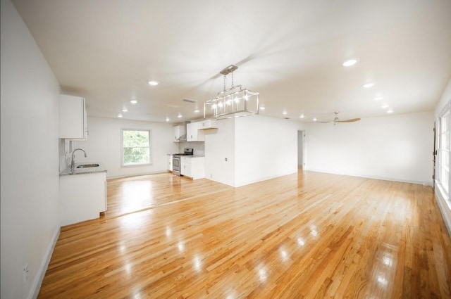 unfurnished living room featuring ceiling fan, sink, and light wood-type flooring