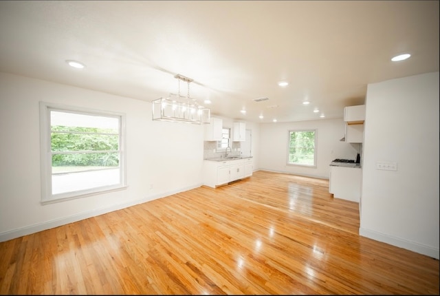 unfurnished living room featuring light hardwood / wood-style floors, sink, and a chandelier