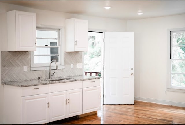 kitchen featuring hardwood / wood-style floors, light stone countertops, tasteful backsplash, and plenty of natural light