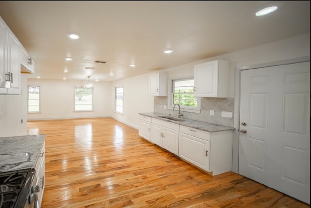 kitchen featuring sink, light hardwood / wood-style flooring, white cabinets, and backsplash