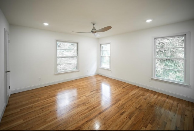 spare room with a healthy amount of sunlight, hardwood / wood-style floors, and ceiling fan