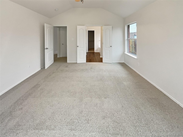 unfurnished bedroom with vaulted ceiling and carpet floors