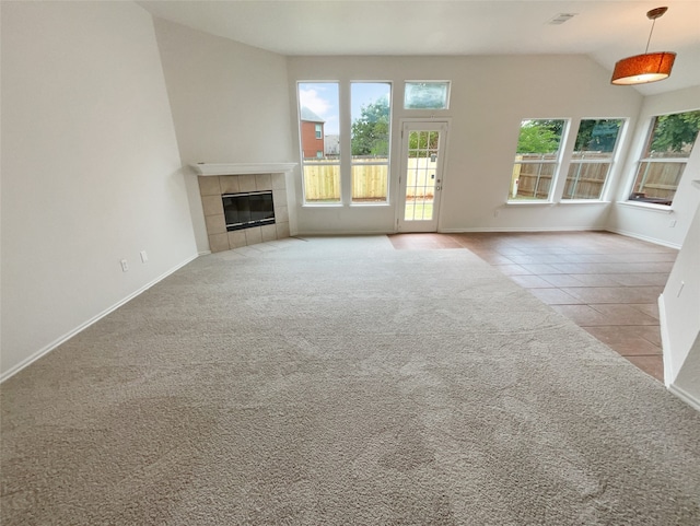 unfurnished living room with a tiled fireplace, light colored carpet, and high vaulted ceiling