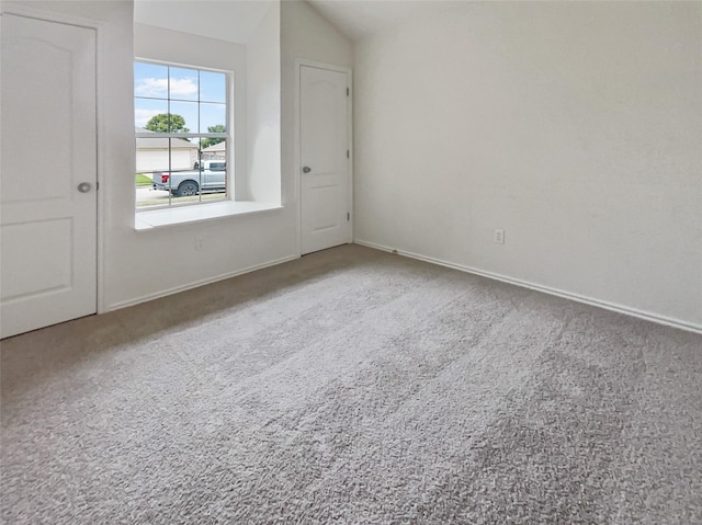 carpeted empty room featuring vaulted ceiling