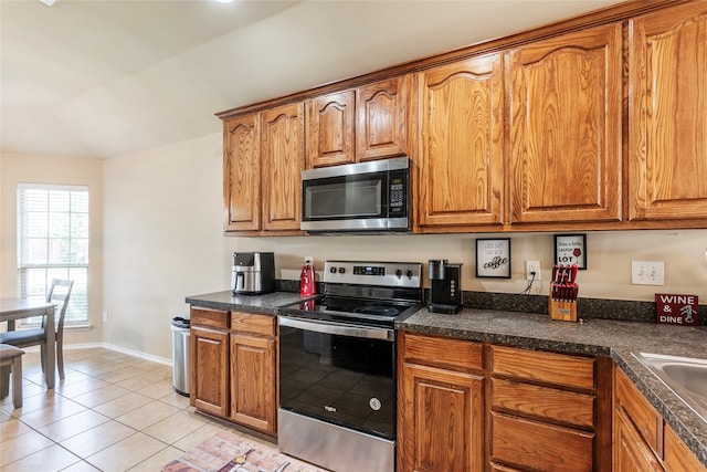 kitchen with lofted ceiling, light tile patterned floors, and appliances with stainless steel finishes