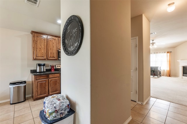 kitchen featuring ceiling fan, light carpet, and dark stone counters