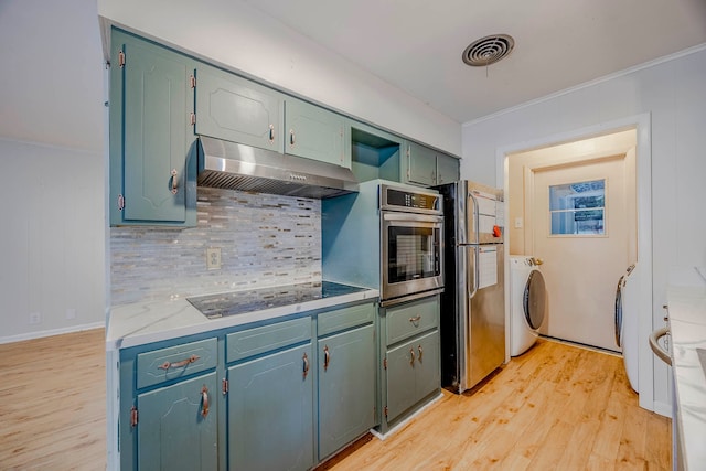 kitchen featuring light wood-type flooring, decorative backsplash, crown molding, appliances with stainless steel finishes, and washer / clothes dryer