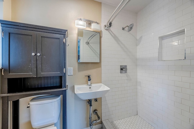 bathroom with sink, tiled shower, and toilet