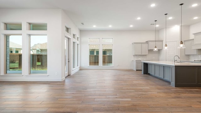 kitchen featuring a healthy amount of sunlight, decorative light fixtures, sink, and light hardwood / wood-style flooring