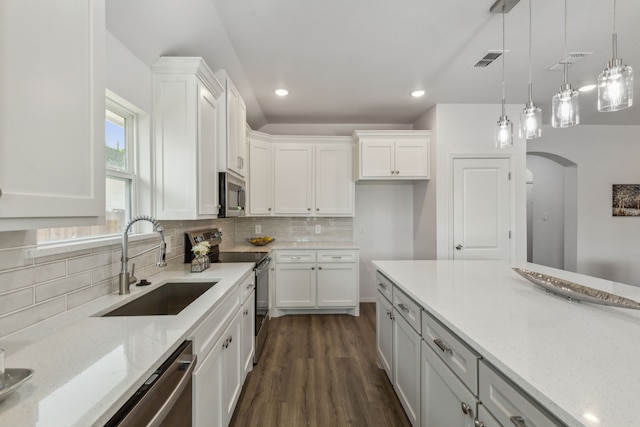 kitchen featuring light stone counters, white cabinetry, appliances with stainless steel finishes, pendant lighting, and sink