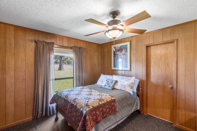 carpeted bedroom featuring a textured ceiling, ceiling fan, and wooden walls