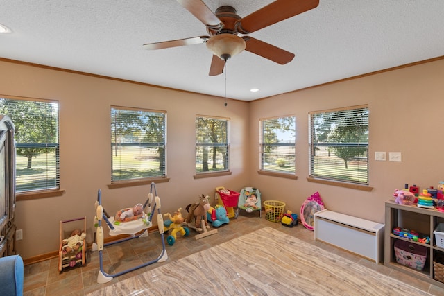 game room featuring light tile patterned flooring, a textured ceiling, ceiling fan, and crown molding