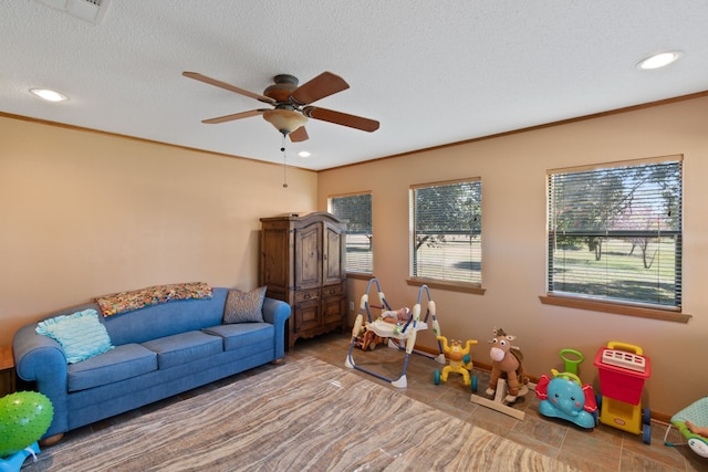 playroom featuring a textured ceiling, crown molding, tile patterned flooring, and ceiling fan