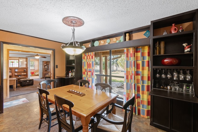 tiled dining area with a textured ceiling, ceiling fan, and crown molding