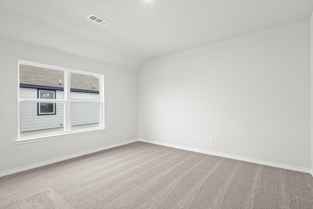 carpeted empty room featuring lofted ceiling