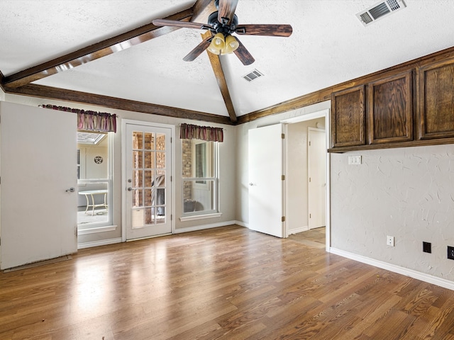 empty room featuring light hardwood / wood-style flooring, lofted ceiling with beams, a textured ceiling, and ceiling fan