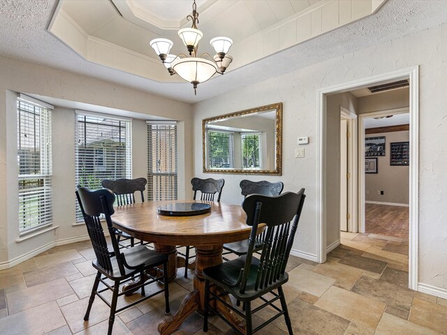 dining room with a tray ceiling, light hardwood / wood-style flooring, a healthy amount of sunlight, and a chandelier