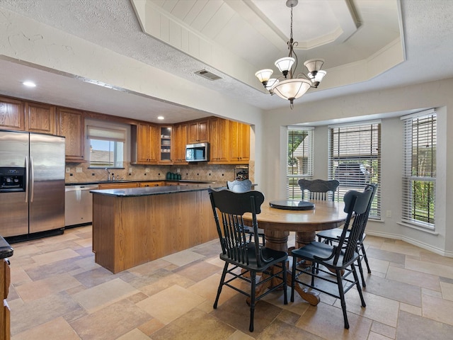 tiled dining area featuring sink, an inviting chandelier, a textured ceiling, and a raised ceiling