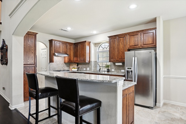 kitchen with a center island, decorative backsplash, appliances with stainless steel finishes, sink, and light stone counters