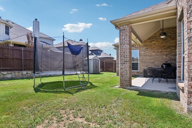 view of yard with ceiling fan, a shed, a patio area, and a trampoline