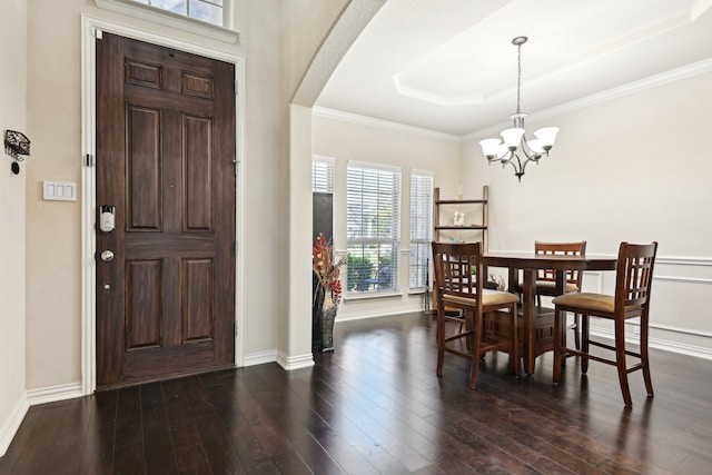 dining room featuring crown molding, a tray ceiling, dark hardwood / wood-style floors, and an inviting chandelier